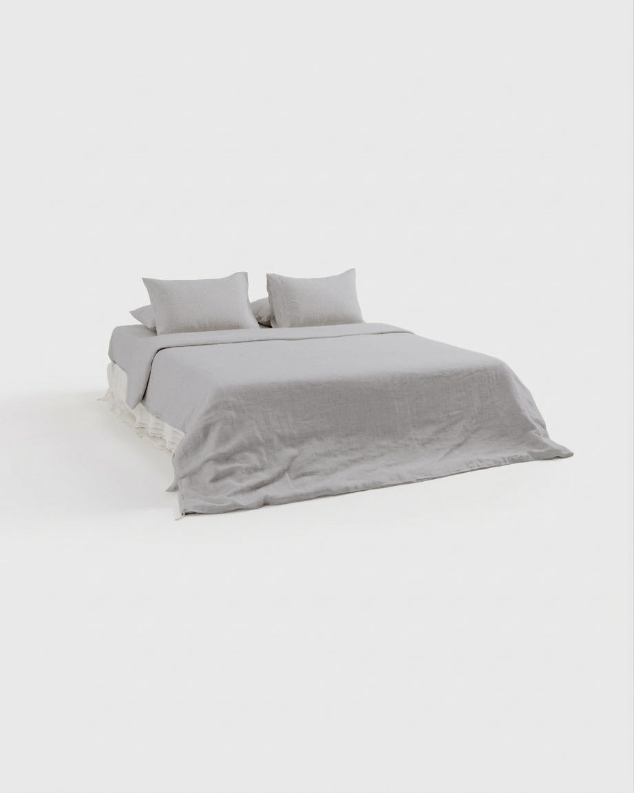 Fog grey French linen bedding set on a bed, side view showing the fitted sheet