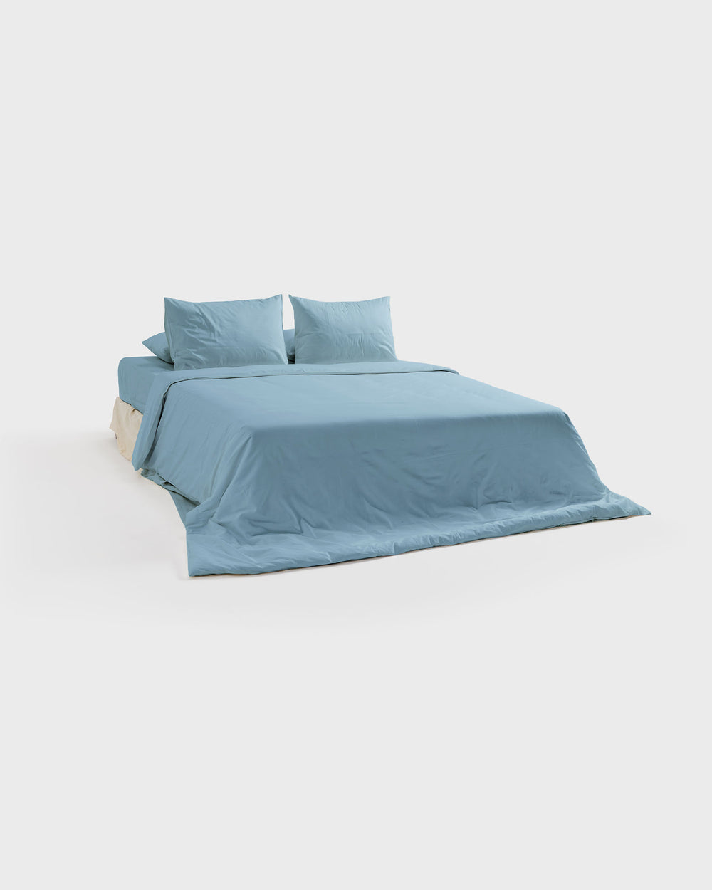 Sky organic cotton sateen bedding on a bed, side view