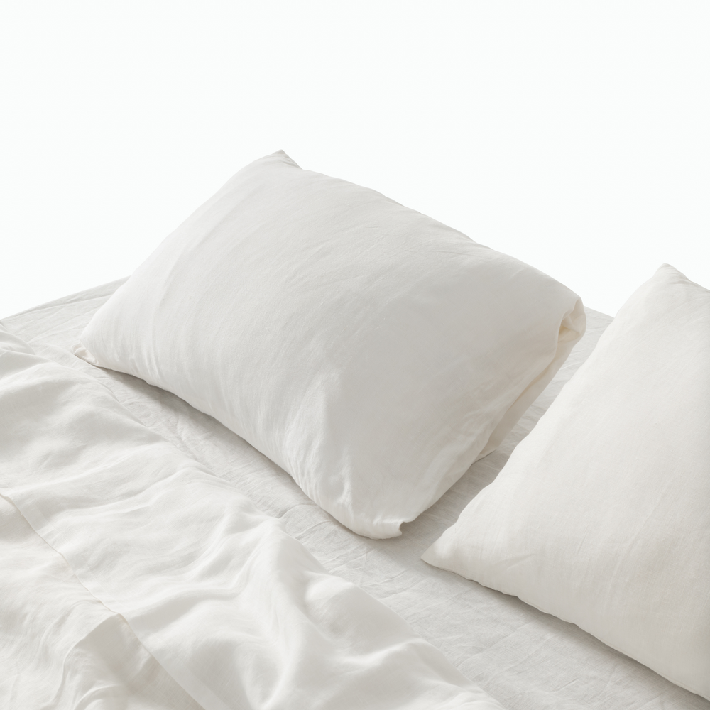 White French linen pillowcases on a crumpled white linen bed