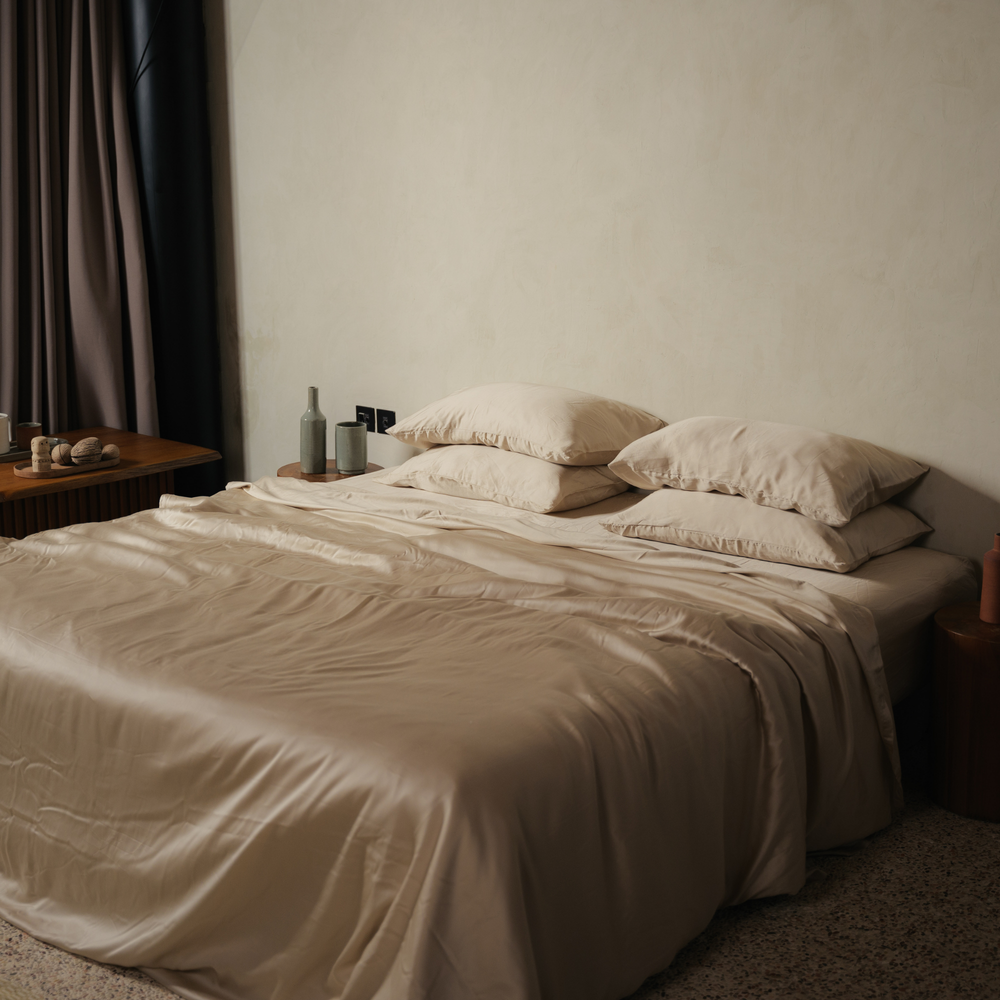 Cream eucalyptus TENCEL bundle set on a bed by a curtained window