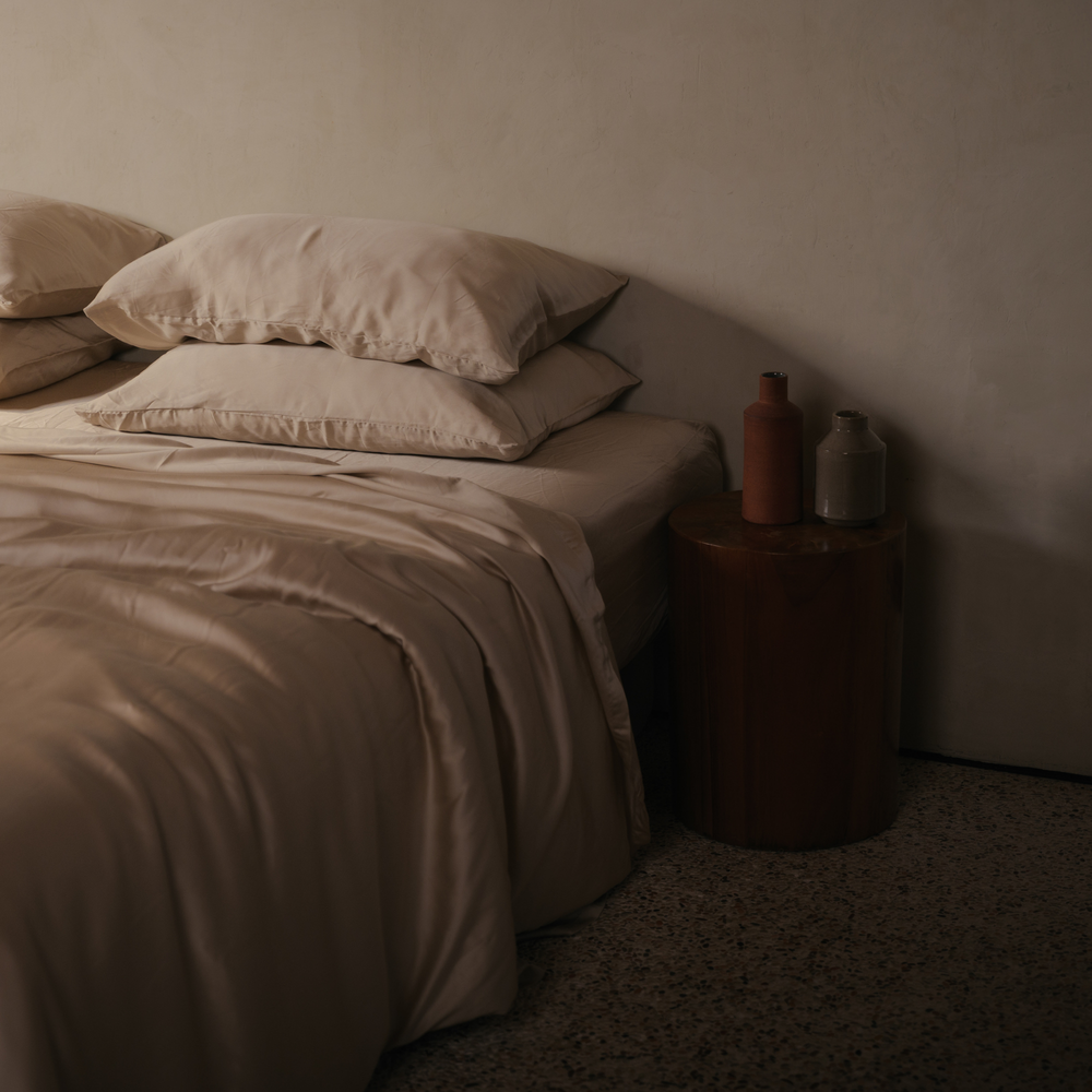 Cream eucalyptus TENCEL pillowcases and sheets beside a wooden side table