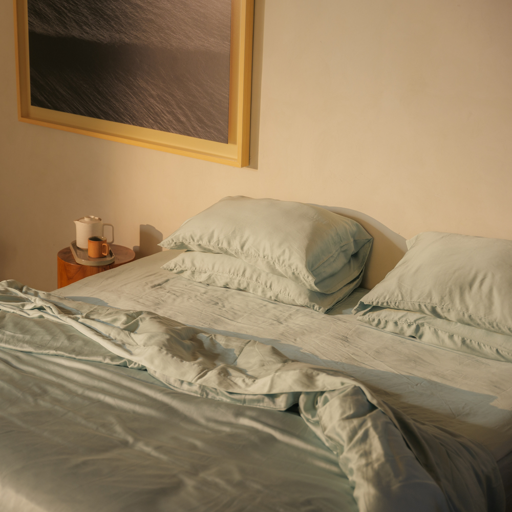 Mint green eucalyptus TENCEL pillows and a turned-down duvet in warm light