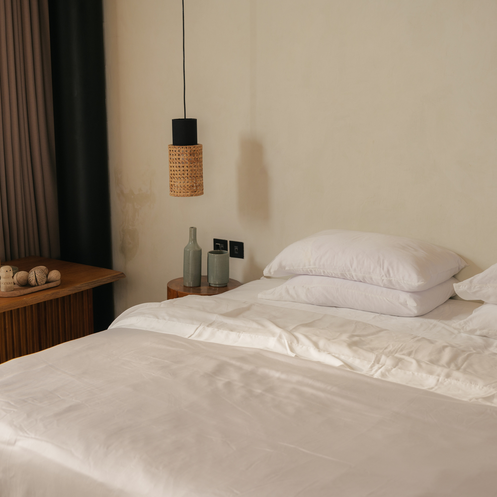 White eucalyptus TENCEL bundle set on a bed under a pendant lamp