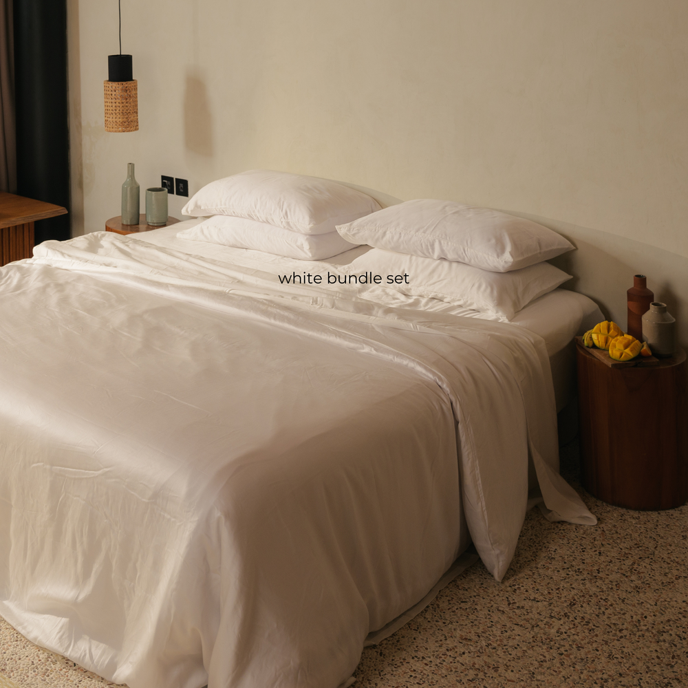 White eucalyptus TENCEL bundle set on a bed with a wooden side table